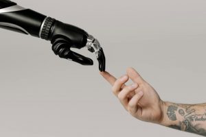 Robotic hand with finger outstretched touching human hand's outstretched finger